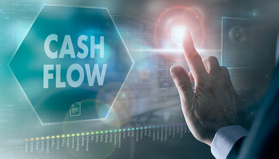 A businessman controlling a futuristic display with a Cash Flow business concept on it.