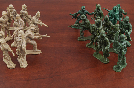 War and military conflict concept. Groups of toy soldiers attack each other.