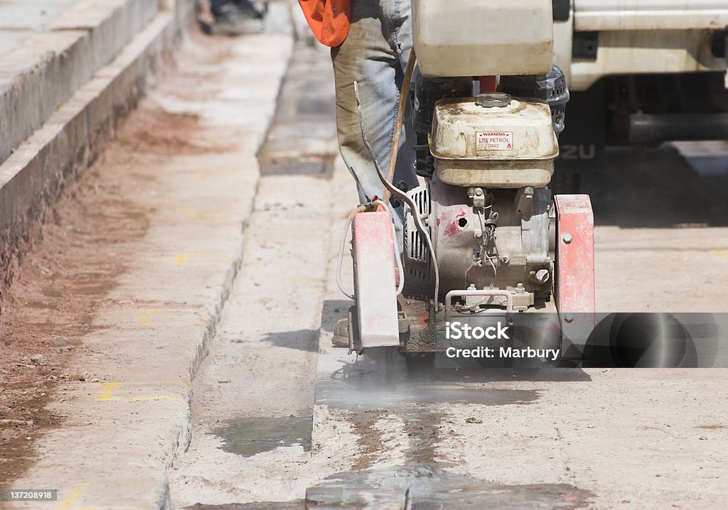 Road works. Construction worker using cutting machine repairing metro link in Manchester. Blue-collar Worker Stock Photo