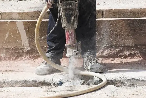 Construction worker using pneumatic drill repairing metrolink in Manchester.