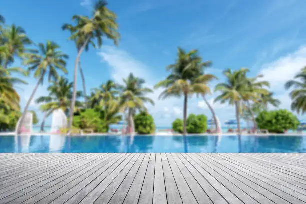 Empty wooden terrace beside tropical beach swimming pool