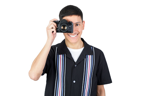 Smiling guy with an analog 35mm camera. Isolated on white background. Latin american 18-20 years old guy.