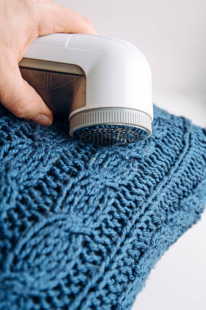 istock Removing shaving lint fuzz from blue woolen coat sweater, wool clothes maintain concept. 1372094656