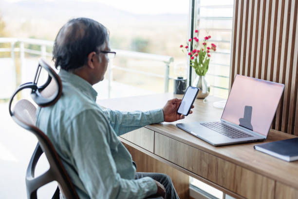 istock Senior Man Using Smart Phone And Laptop At Home 1372096617