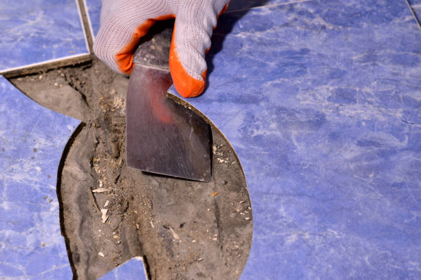 istock Men's hands tear off the split ceramic tiles from the floor with a spatula. 1372096911