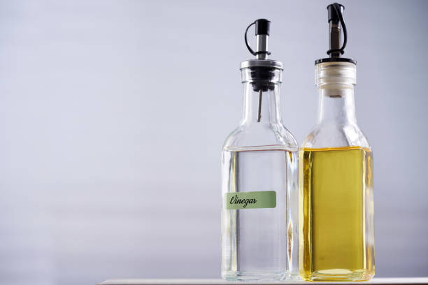 белый уксус и оливковое масло на столешнице из дерева - vinegar bottle herb white стоковые фото и изображения