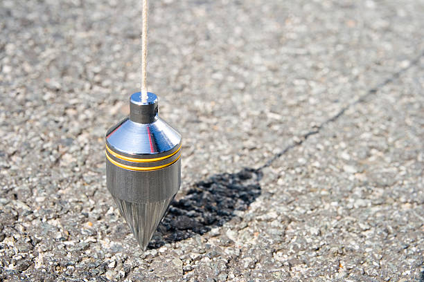 Plumb bob Steel plumb bob (surveyor's equipment) on tarmac. plumb line stock pictures, royalty-free photos & images