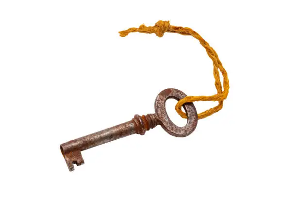 Photo of Vintage keys isolated. Close-up of an old rusty key of an old large padlock hanging on a string isolated on a white background. Antique objects. Macro.