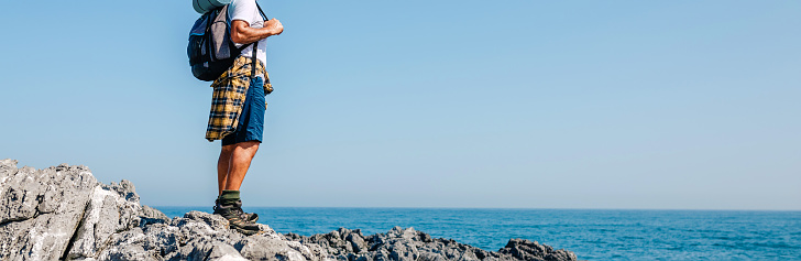 Senior man with backpack hiking looking at sea landscape