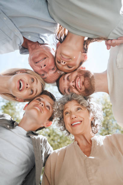 aufnahme einer mehrgenerationenfamilie, die in einem huddle zusammensteht - family grandmother multi generation family nature stock-fotos und bilder