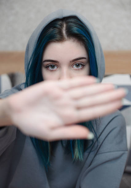 A teenage girl with blue hair covers her face with her hand A teenage girl with blue hair covers her face with her hand. Teenage protest. Depression. depression land feature stock pictures, royalty-free photos & images