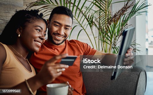 istock Shot of a young couple sitting together in the living room and using a digital tablet for online shopping 1372099560