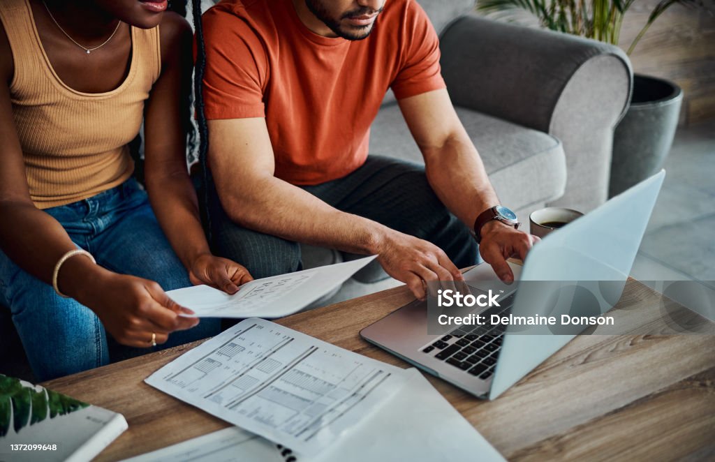 Cropped shot of an unrecognisable couple sitting in the living room and using a laptop to calculate their finances I've got all the paperwork here Tax Stock Photo