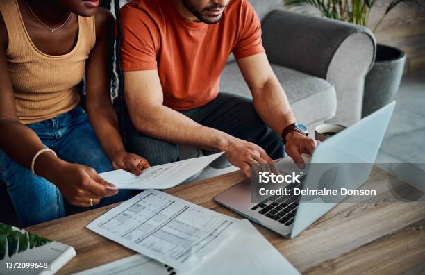 Cropped Shot Of An Unrecognisable Couple Sitting In The Living Room And Using A Laptop To Calculate Their Finances Stock Photo - Download Image Now