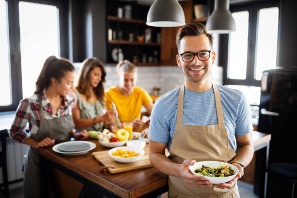 Group of happy friends having fun in kitchen, cooking food together stock photo