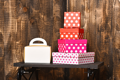 white ladies handbag and pretty sweet presents boxes on black tray on wooden background, copy space