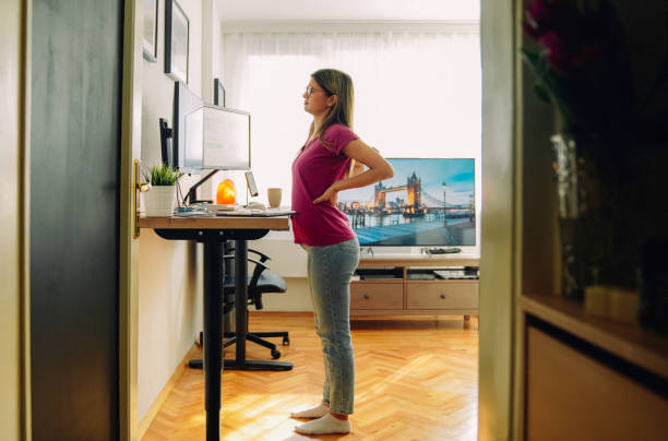istock Woman with back pain working at standing desk home office 1372102005