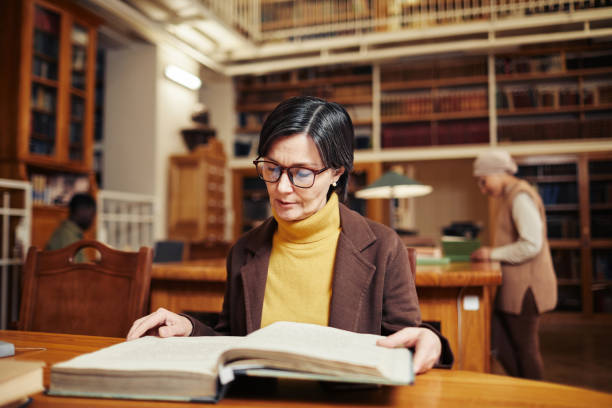 istock Woman Reading Book in Library 1372102025