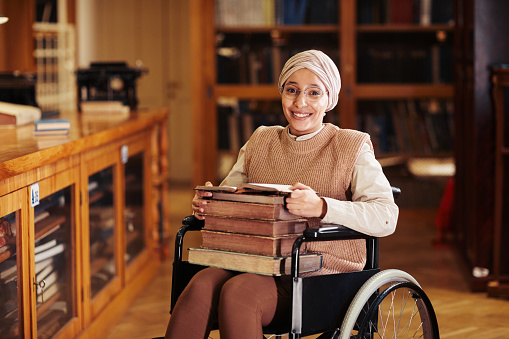 Smiling Woman with Disability Using Wheelchair in Library