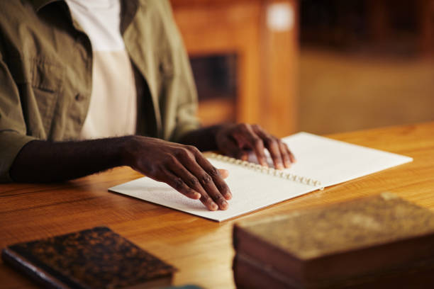 black man reading braille book in library - tillgänglighet blind braille bildbanksfoton och bilder