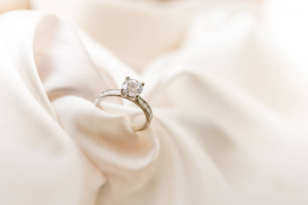 diamond ring on a pastel silk background - diamantring stockfoto's en -beelden