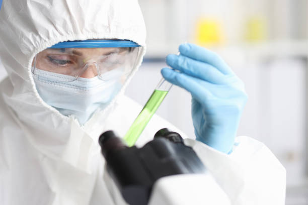 보호복을 입은 과학자가 독성 액체로 테스트 튜브를 보유하고 있습니다. - protective suit adult adults only biotechnology 뉴스 사진 이미지