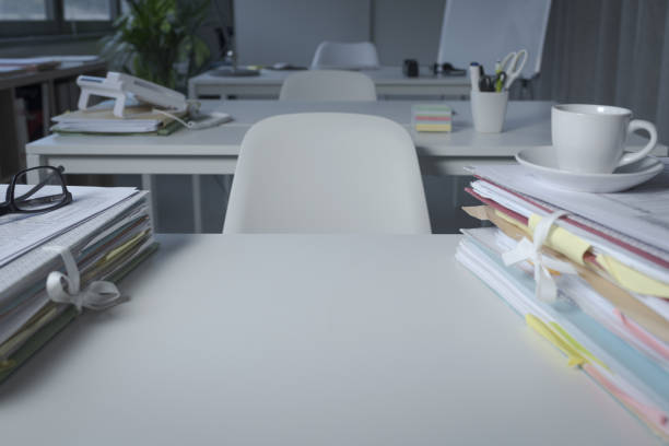A neat office desk with a computer monitor, keyboard, and a glass of water beside a closed notebook and pen, reflective of professional organizational skills.