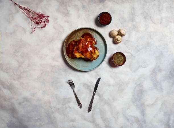 Chicken with barbecue sauce and cheddar cheese top view, on gray background, knife and fork on the table