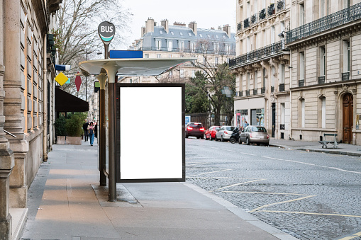 A bus stop in a city with a blank advertisement placard
