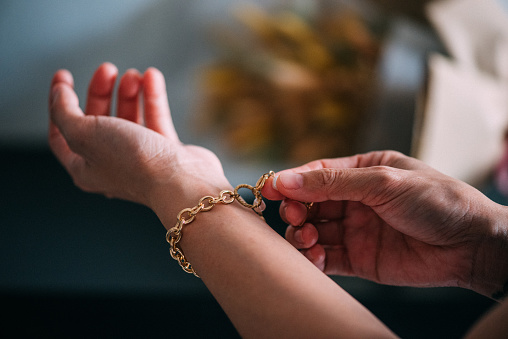 Una mano de mujer asiática que muestra accesorios de lujo como pulsera de oro photo