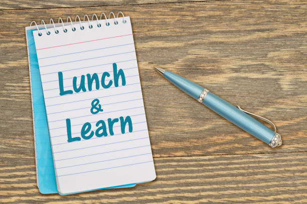 istock Lunch and Learn message on retro lined paper notepad on a weathered wood desk 1372106386