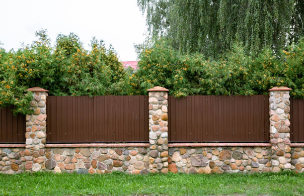istock Stone fence with brown metal profile. Corrugated surface with vertical lines. Copy space. Private property fencing security. Opaque hedge. Outdoor exterior. High. Side view. Country or chalet style 1372107543