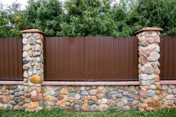 istock Stone fence with brown metal profile. Corrugated surface with vertical lines. Copy space. Private property fencing security. Opaque hedge. Outdoor exterior. High. Side view. Country or chalet style 1372107562