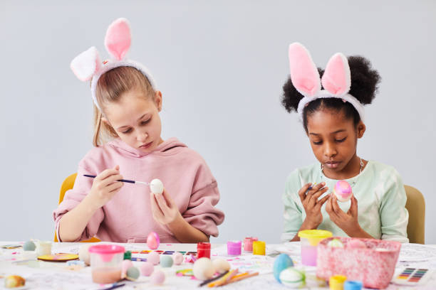 istock Two Girls Painting Easter Eggs Minimal 1372111450