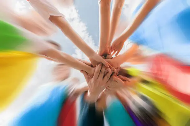 Hands of kids sports team stacked on top of each other. Youth team celebrating a victory. Motivated children's sports team raising hands up. Young school football team. Happy kids playing sports