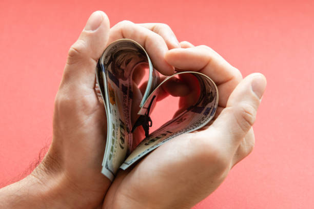 several 100 dollar bills folded in the shape of a heart in male hands. love of money, greed, business, wealth several 100 dollar bills folded in the shape of a heart in male hands. love of money, greed, business, wealth. valentinstag stock pictures, royalty-free photos & images