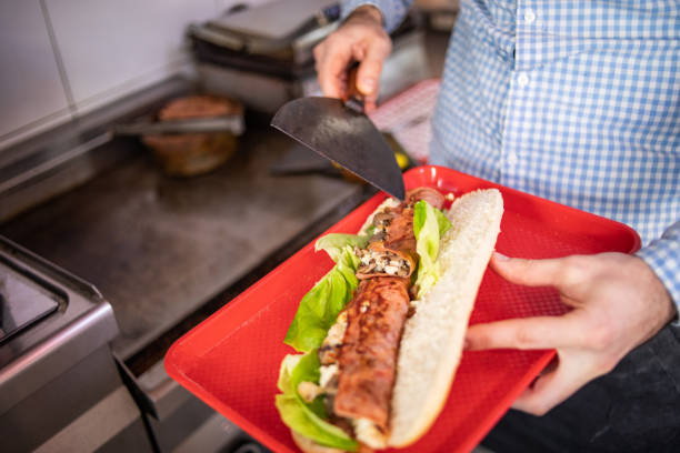 istock A fast food restaurant worker preparing a sandwich 1372113938