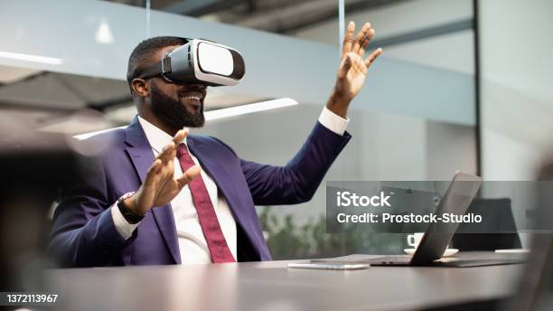 Excited Black Businessman Sitting At Workdesk Using Vr Glasses Stock Photo - Download Image Now