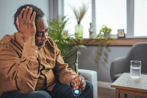 Unhappy middle aged retired grandfather suffering from headache disease indoors. Frustrated unhealthy senior mature man touching head, having painful feelings sitting alone at home. Unhappy middle aged retired grandfather suffering from headache disease indoors. chronic illness stock pictures, royalty-free photos & images