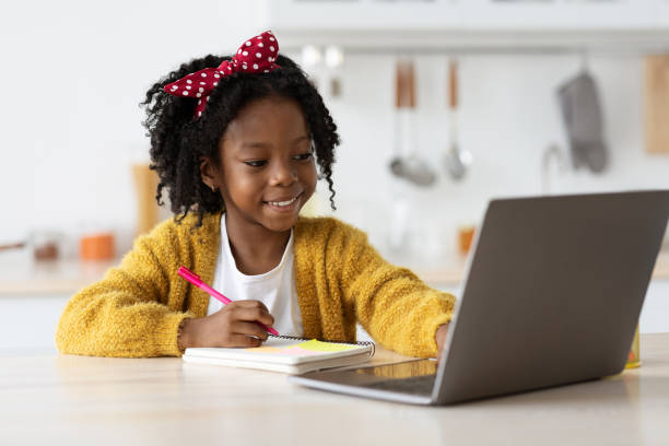 istock Cute Preteen Black Girl Writing In Notepad While Study Online With Laptop 1372115397