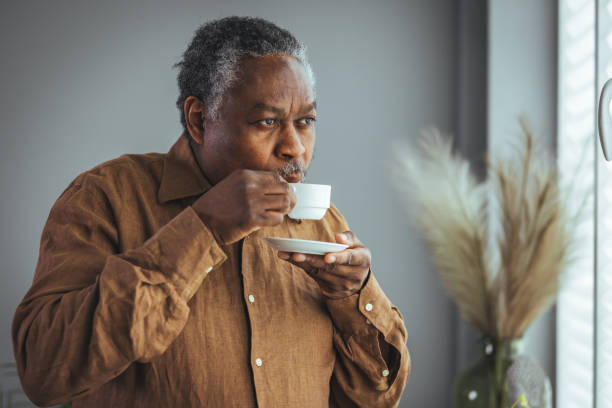 istock Older African man drinking coffee while standing by the window in the morning 1372116323