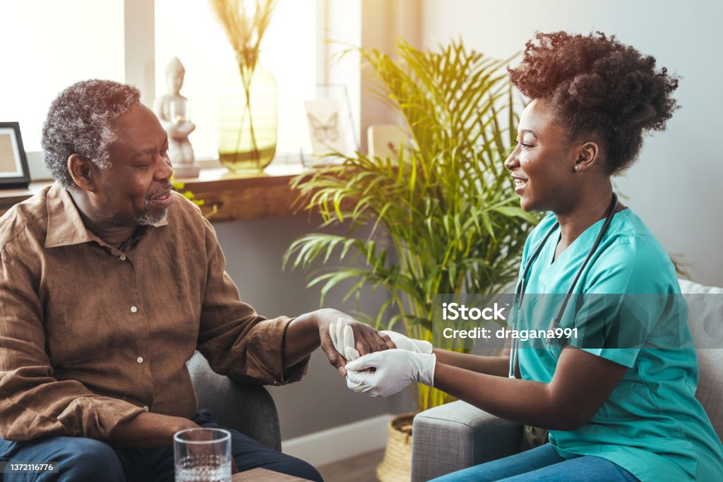 Closeup shot of a young woman holding a senior man's hands in comfort. Closeup of a support hands. Closeup shot of a young woman holding a senior man's hands in comfort. Female carer holding hands of senior man Home Caregiver Stock Photo