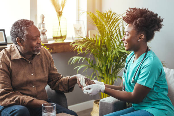 zbliżenie przedstawiające młodą kobietę trzymającą w komforcie ręce starszego mężczyzny. - community outreach aging process human age retirement zdjęcia i obrazy z banku zdjęć