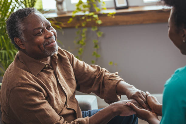 female carer holding hands of senior man - holding hands human hand senior adult consoling imagens e fotografias de stock