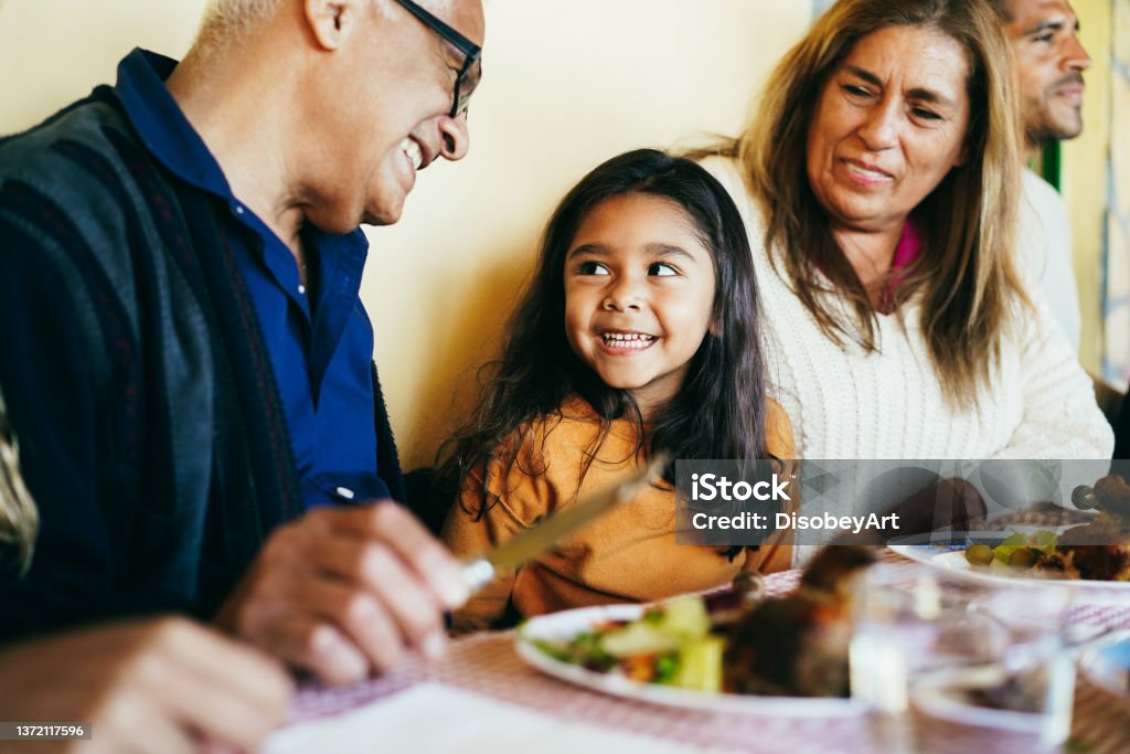 Happy grandparents eating with grand-daughter at home patio - Focus on girl face Eating Stock Photo