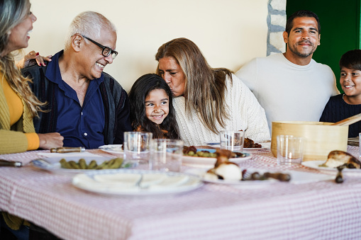 Latin grandmother kissing her grand-daughter during home family dinner - Focus on girl face