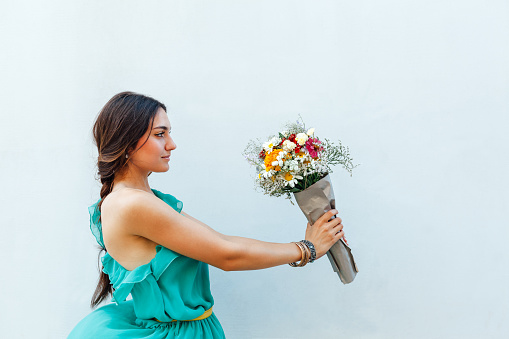 Beautiful young woman holding a bouquet of flowers with copy space.