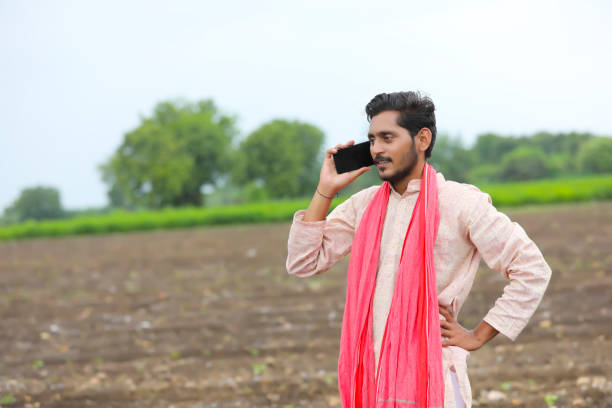 Indian farmer talking on smartphone at agriculture field.