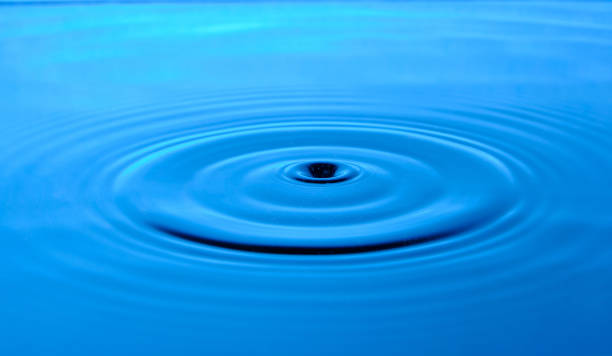 istock Bright blue background with diverging circles from dropped drop on surface water. 1372121042