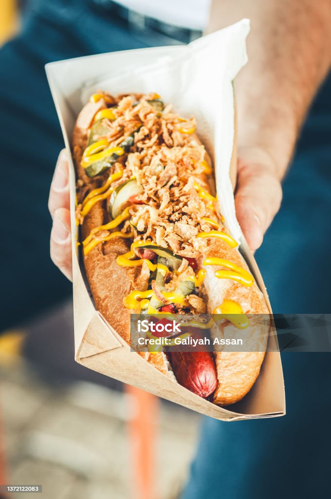 Freshly prepared hotdog with lush salsa cauce in a paper box. Food delivery or take away food concept. Advice Stock Photo